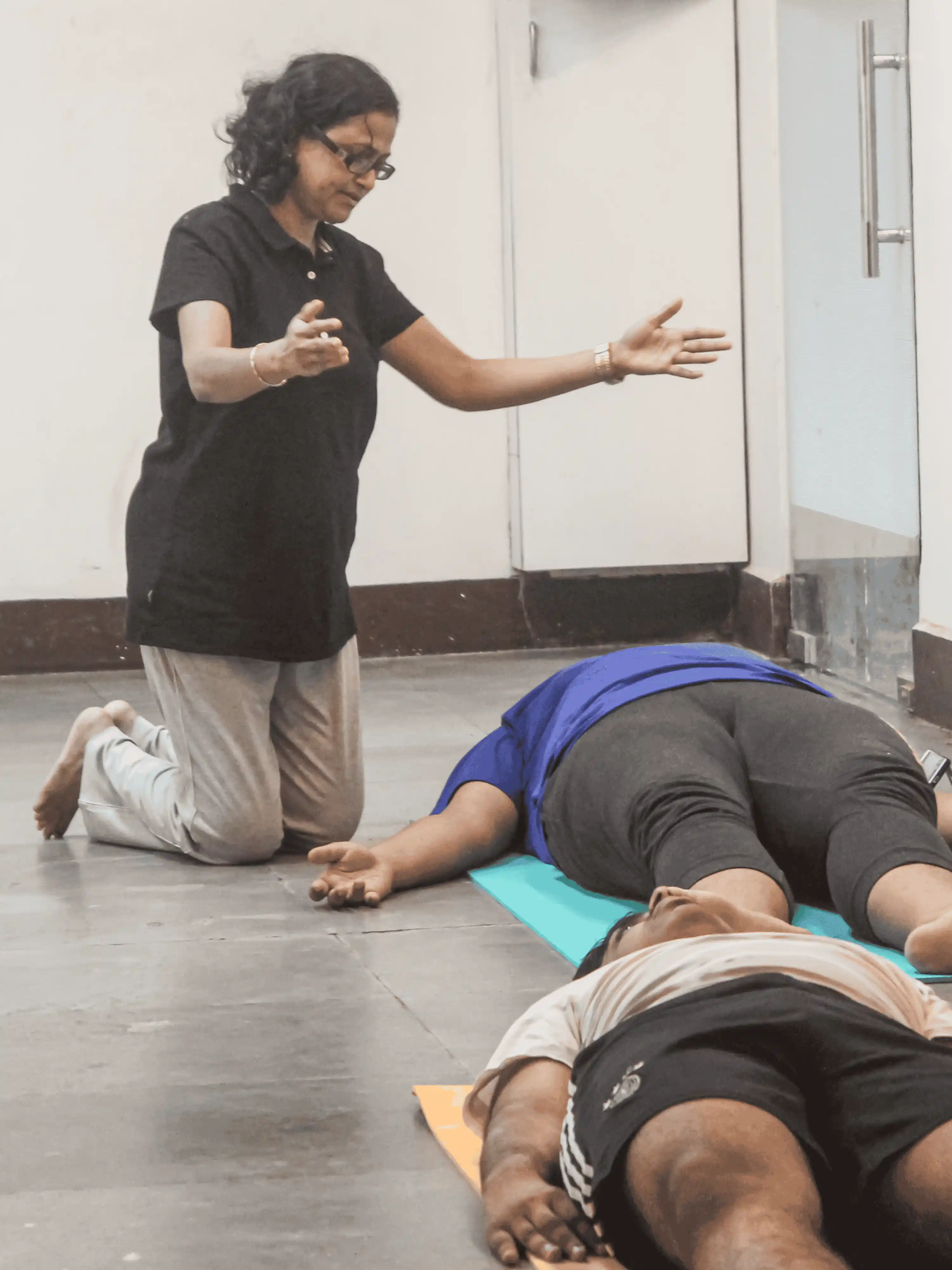 Yoga teacher assisting a student with physical alignment on a yoga mat