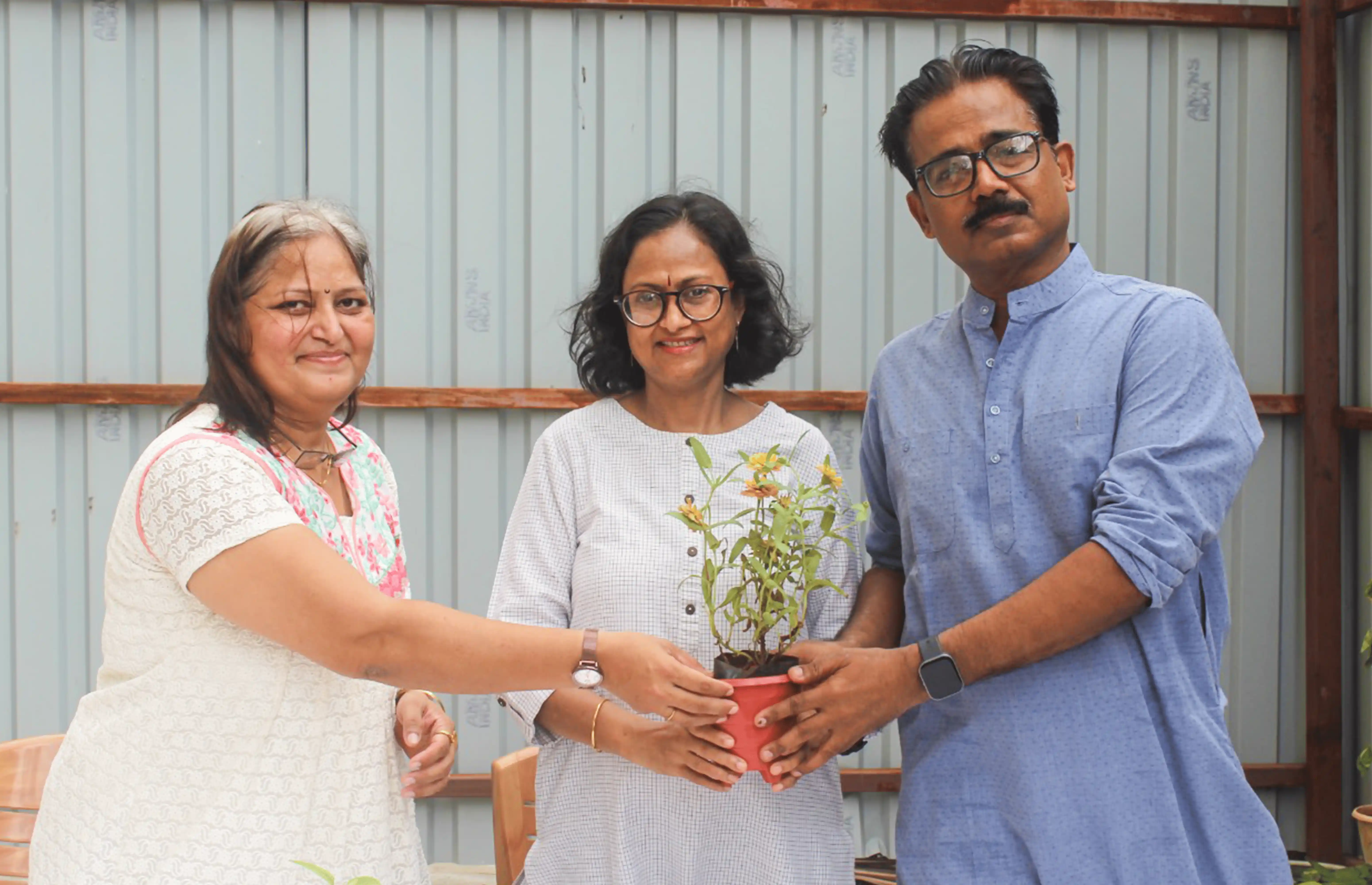 Yoga community members holding a small plant together symbolizing growth