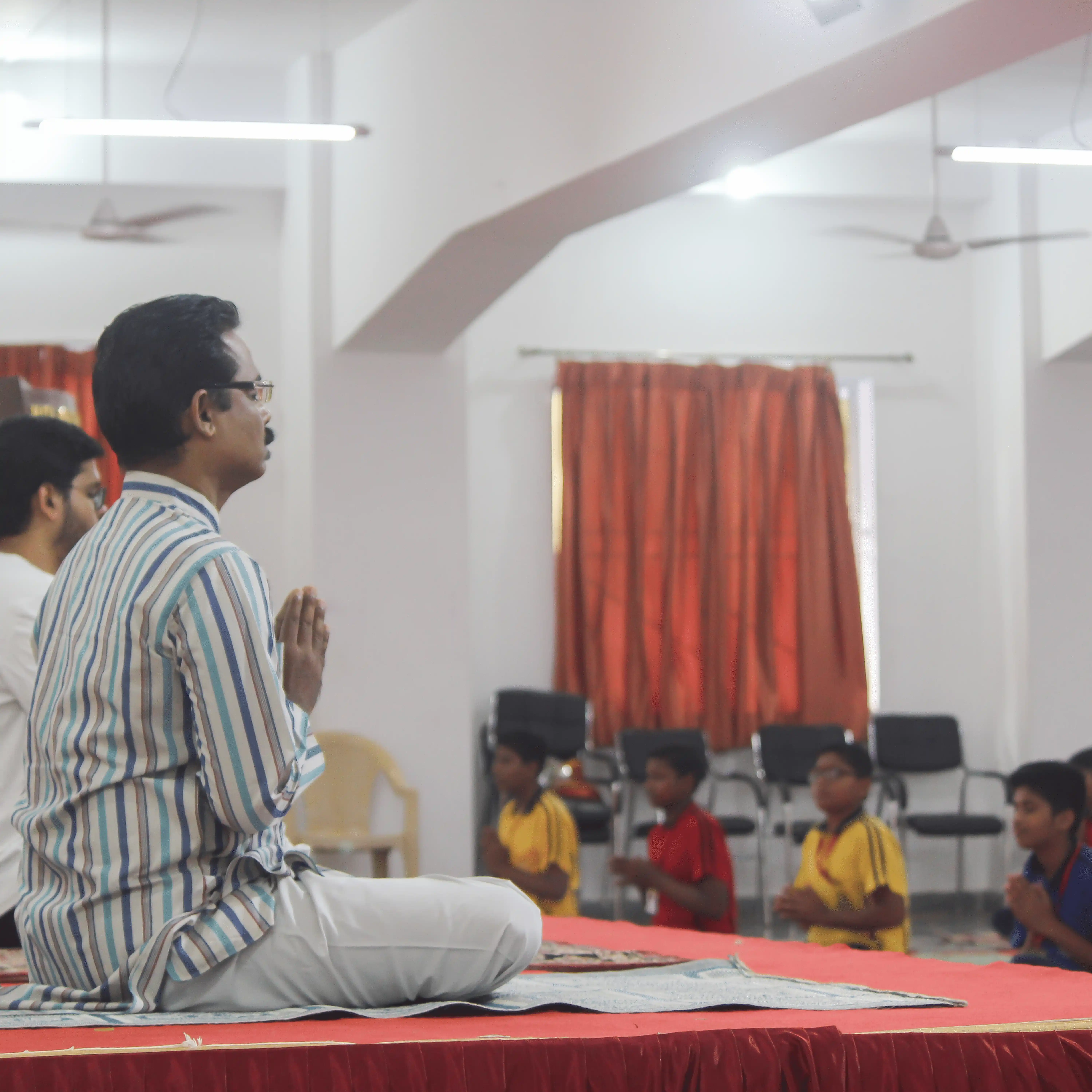 Yoga master leading a large group meditation session from a stage